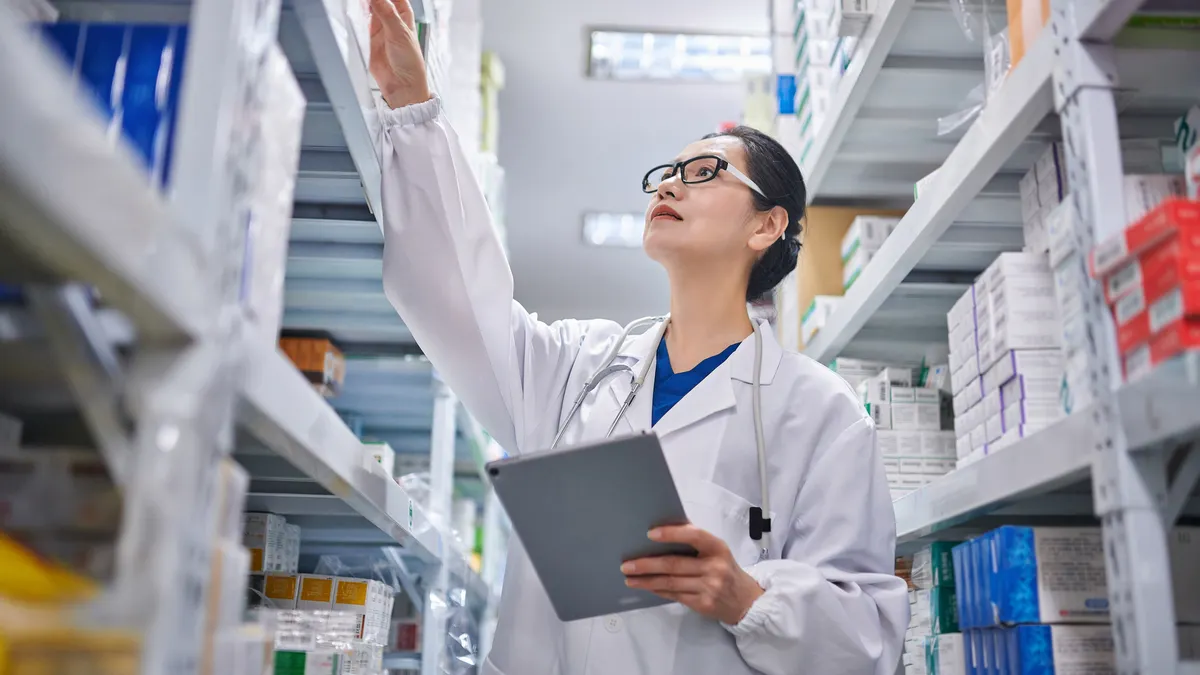 A pharmacist takes inventory of prescription drug cartons.