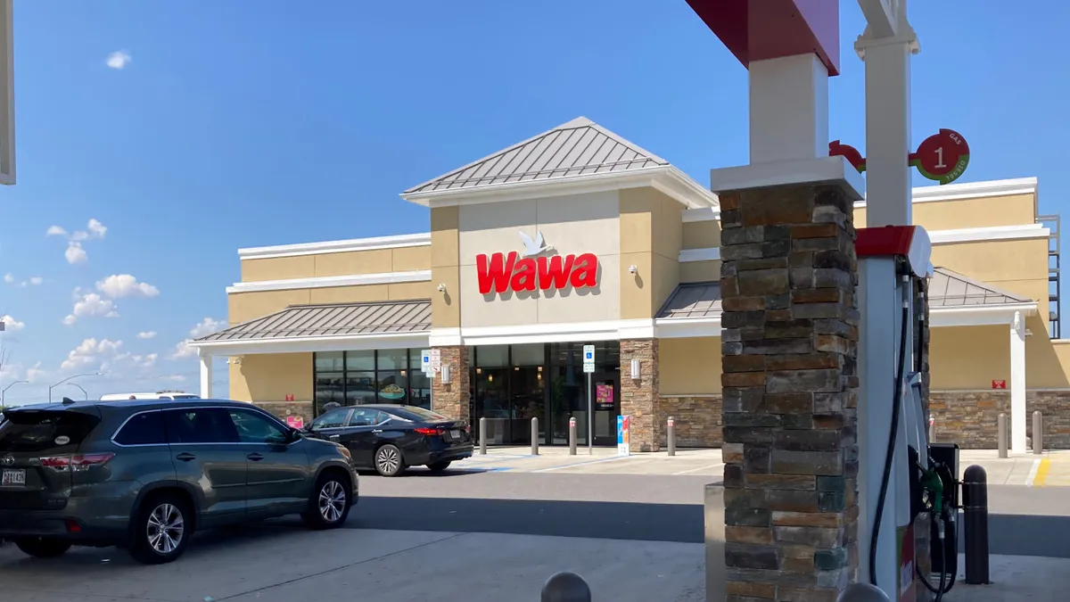 A photo of a convenience store in the background with fuel pumps in the foreground. A sign on the building says "Wawa."