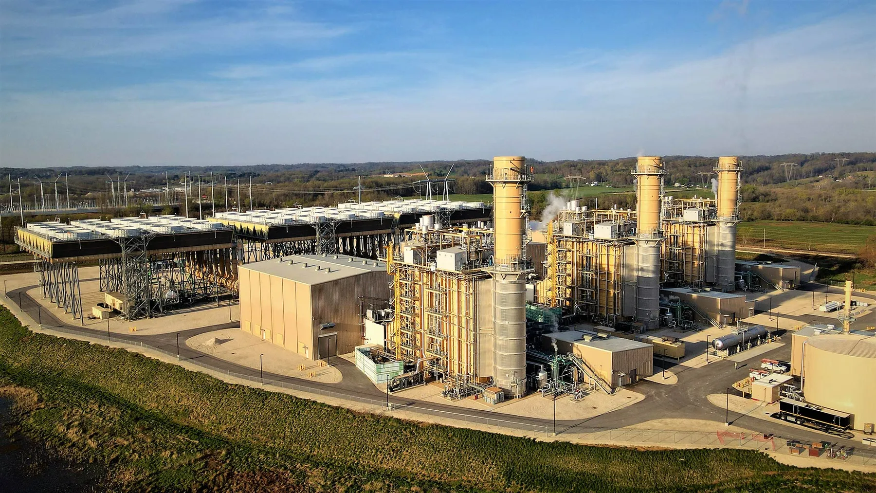 An industrial complex with three smokestacks in a rural setting.