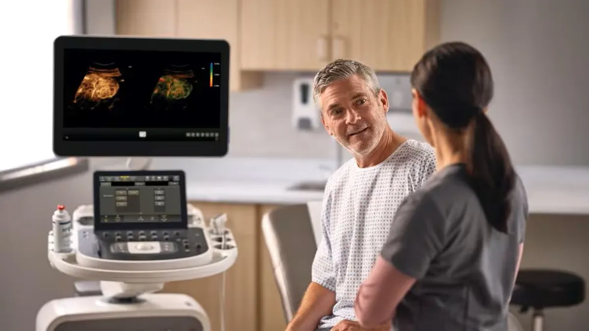 Two people talk while a screen displays a medical image.