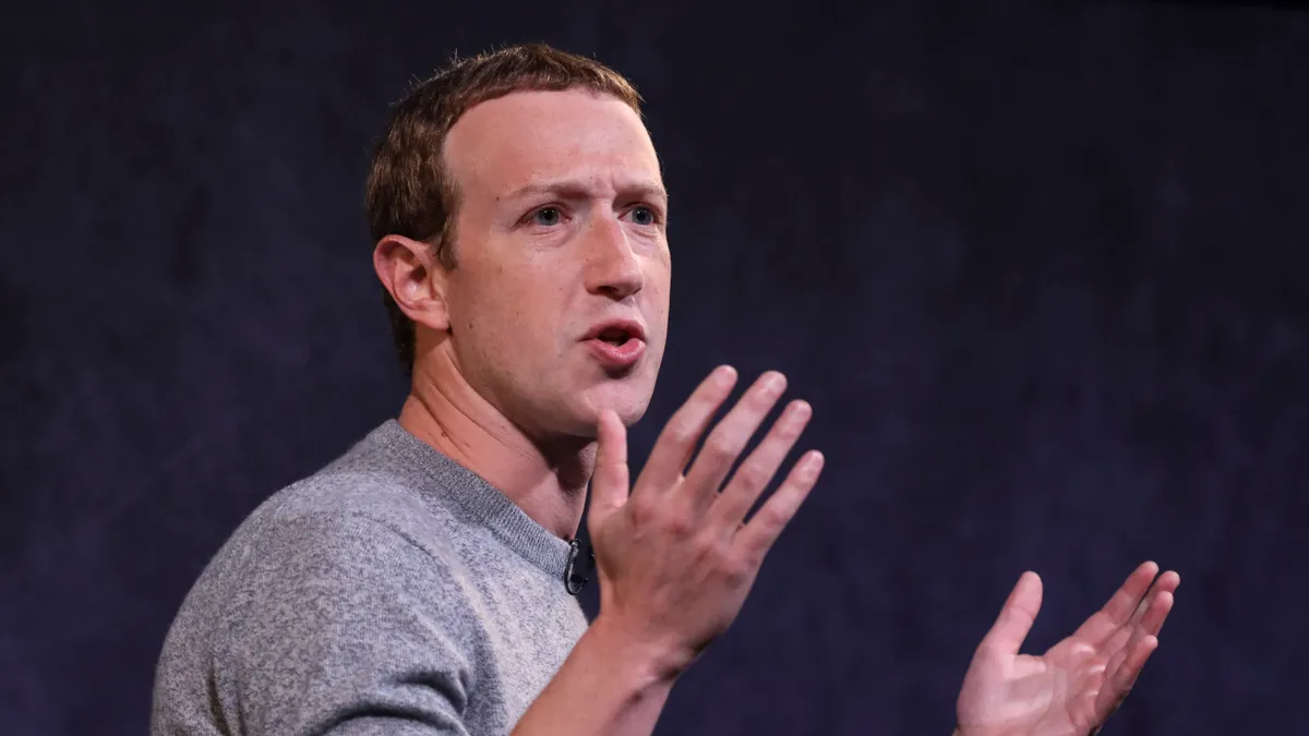 Meta Platforms CEO Mark Zuckerberg, wearing a gray sweater, puts his hands up during a presentation.