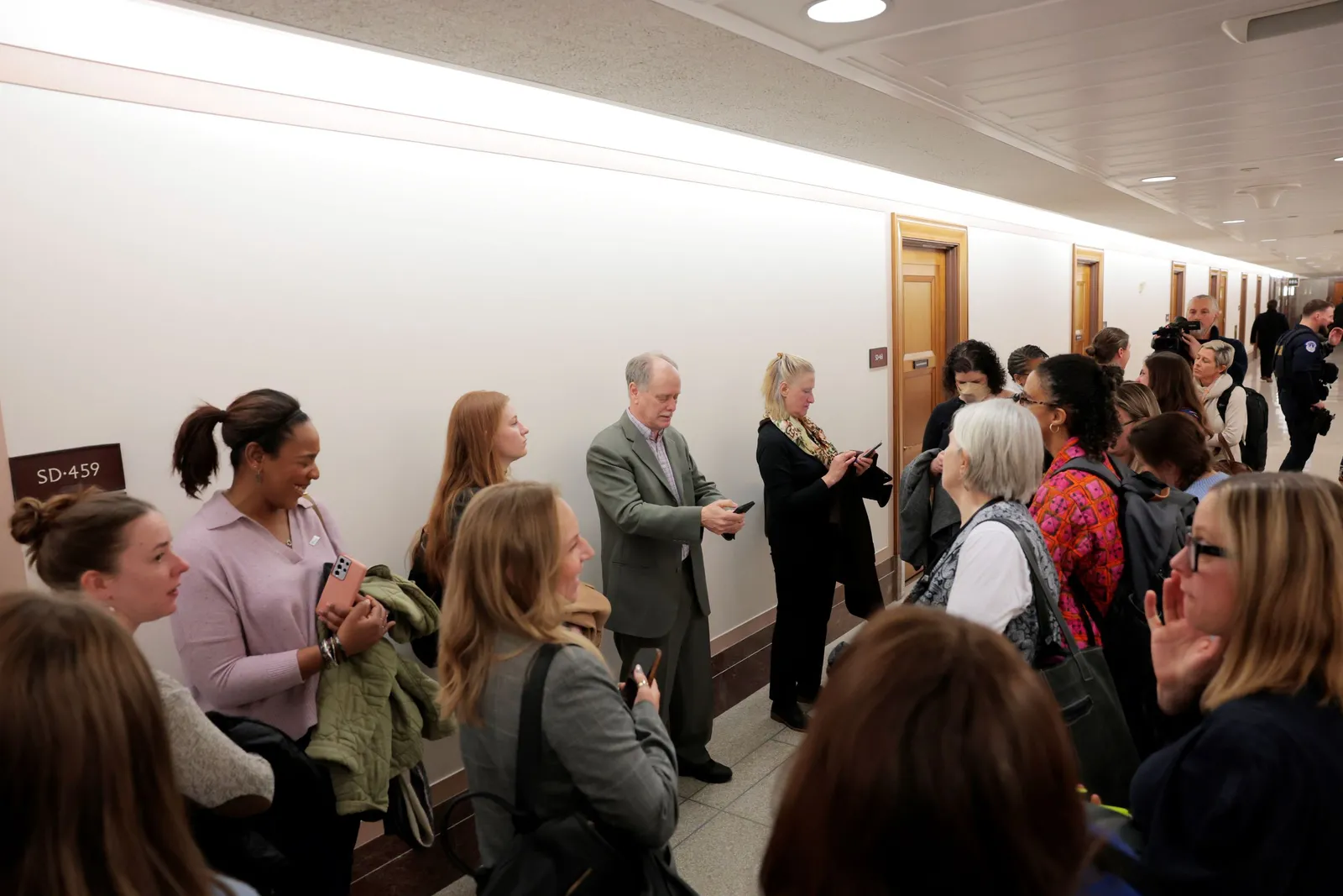 Laid off federal workers gather in a hallway.