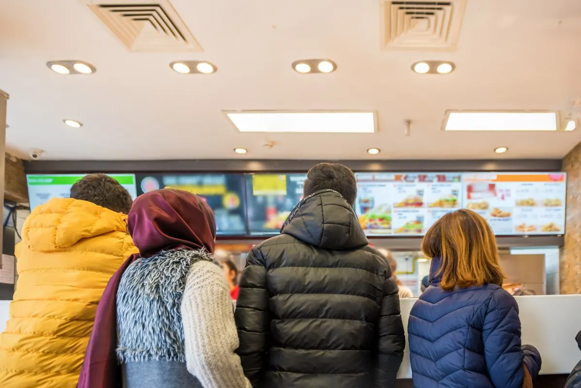 Four customers wait in line at a fast food restaurant.