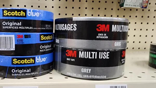 A stack of three Scotch blue painters tape on the left, and a stack of two grey 3M duct tape on the right, on a store shelf.
