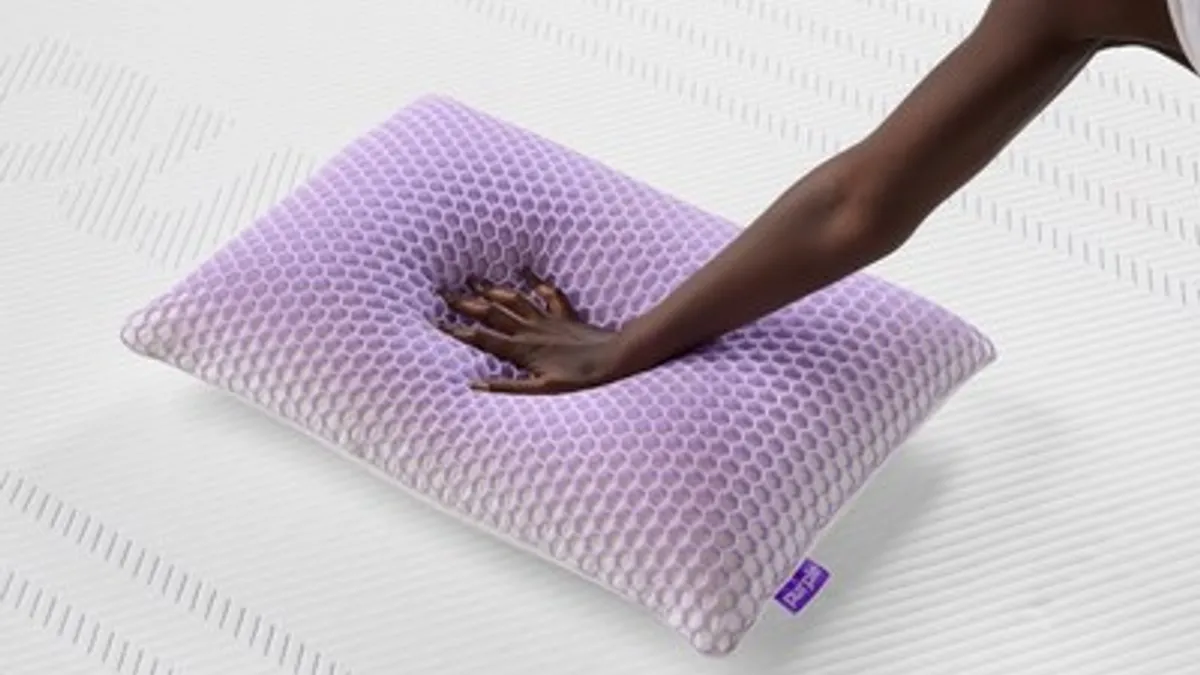 Hand pushing on a light purple memory foam pillow