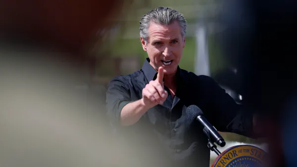 California Gov. Gavin Newsom motions from behind a podium.