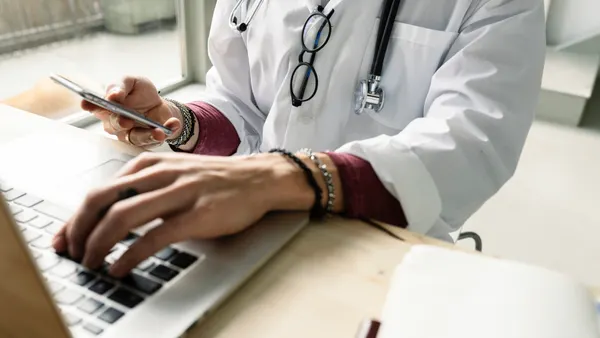 close-up of a female doctor using computer and smartphone