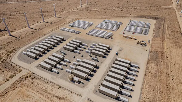 Battery storage containers sit near wind turbines.