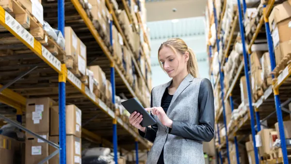 A pensive young woman supervisor working on-line in warehouse