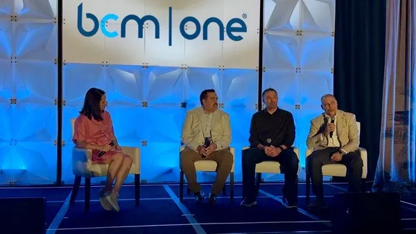 four people sitting and speaking onstage in a panel