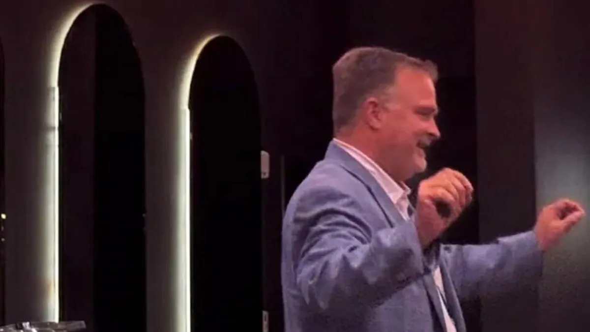 a man in a suite gesticulates while speaking