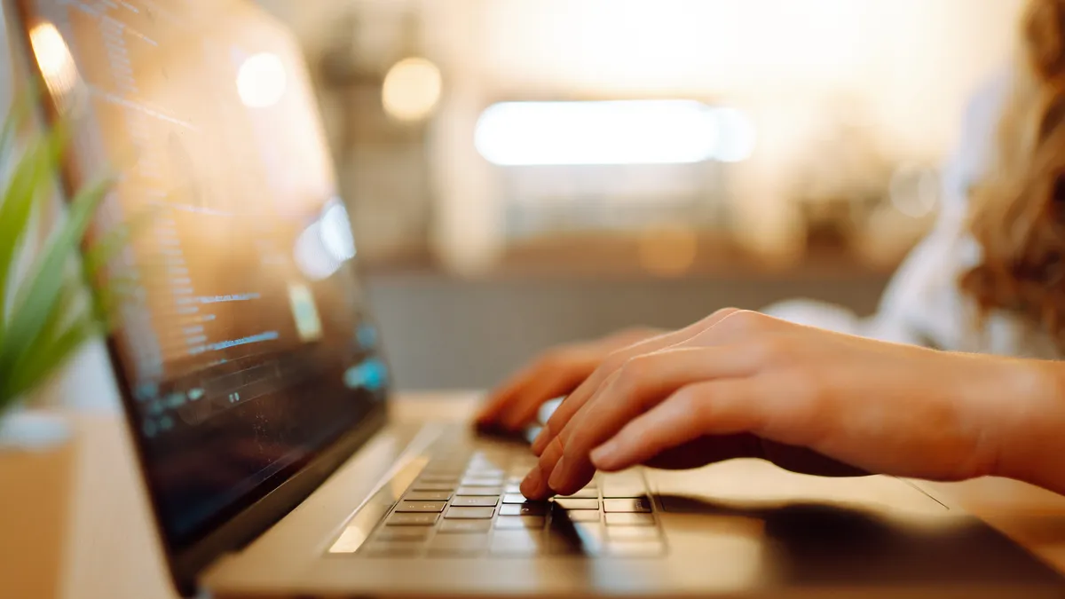 Hands type on a laptop keyboard.