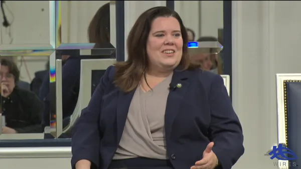 A woman speaks from a chair.