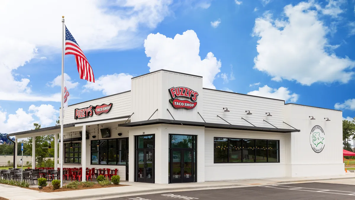 A Fuzzy's Taco Shop store with the American flag flying over it.