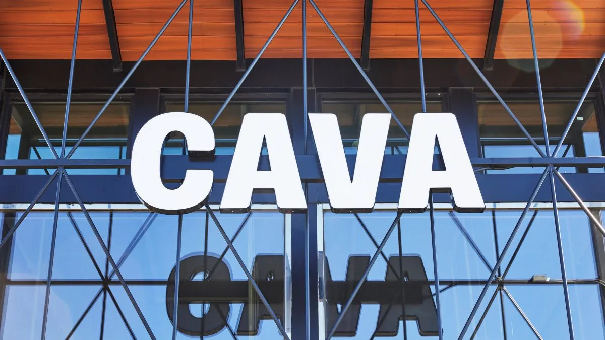 A white sign that says Cava in front of a glassed facade building.