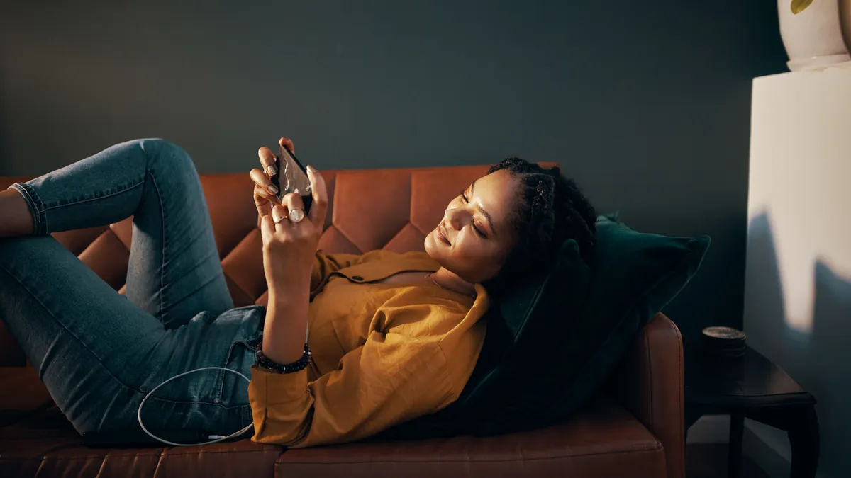 A person laying on a couch while scrolling on their phone