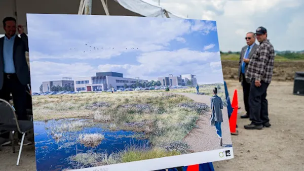 A rendering of a future hospital is propped on an easel at a groundbreaking ceremony.