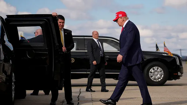 President Donald Trump walks to his car wearing a "Make America Great Again" hat.