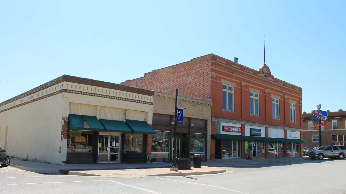 A wide street with one and two-story retail buildings on a sunny day.
