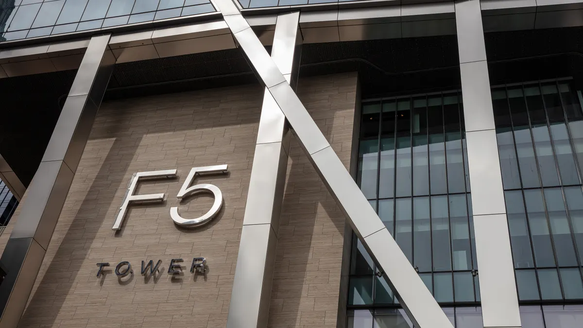 The words "F5 Tower" are displayed on the outside of a metal-and-wood building with many windows.