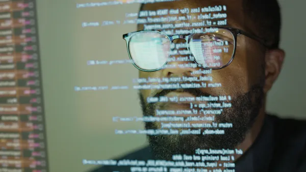 Man studying see-through display depicting computer code.