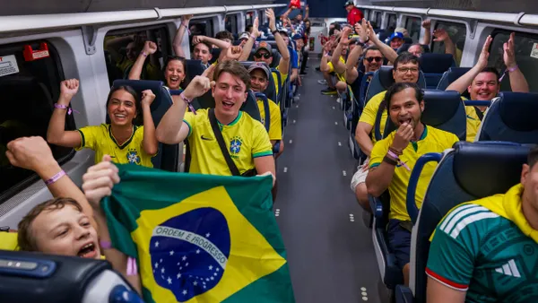 People wearing yellow shirts cheer as they ride a bus.