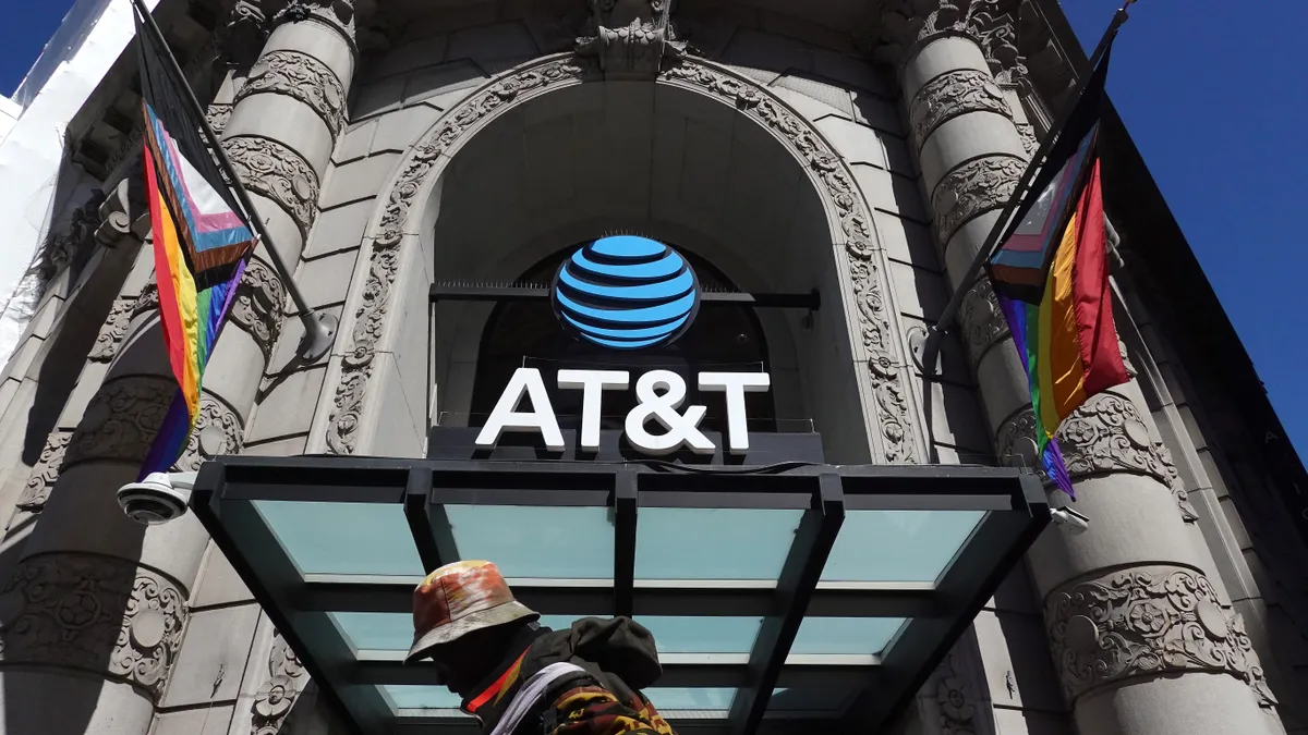 A pedestrian walks by a sign posted in front of an AT&T store.