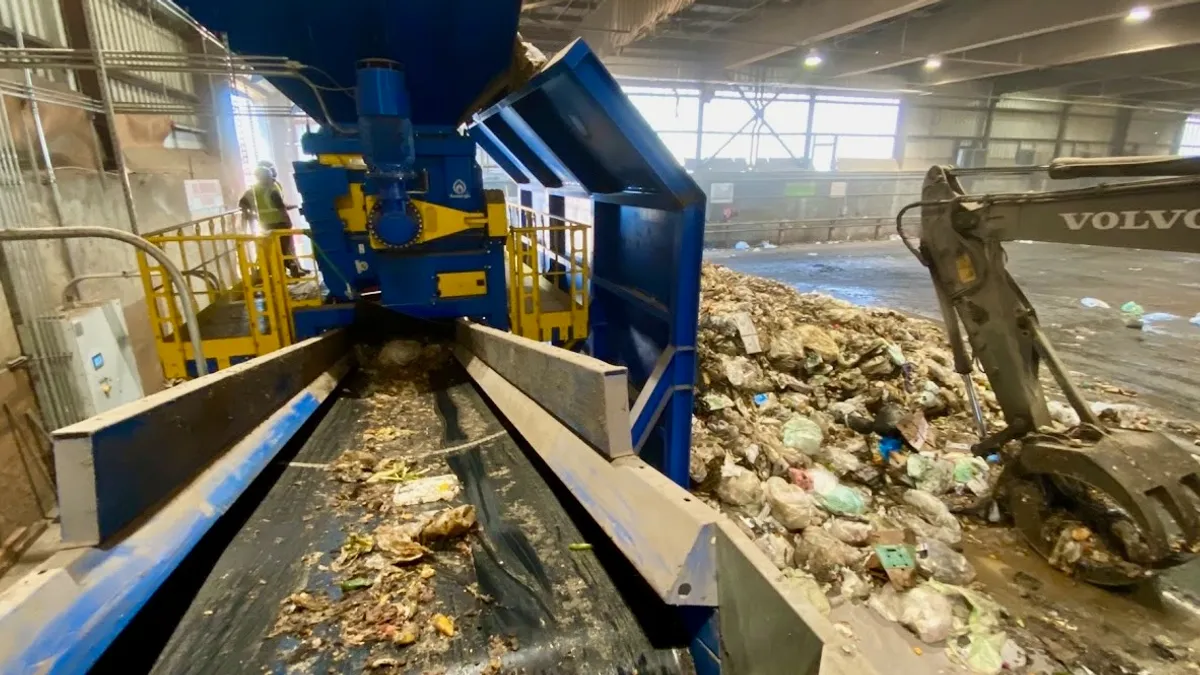 Conveyor belt to process organic waste via Anaergia OREX machine, within larger transfer station facility