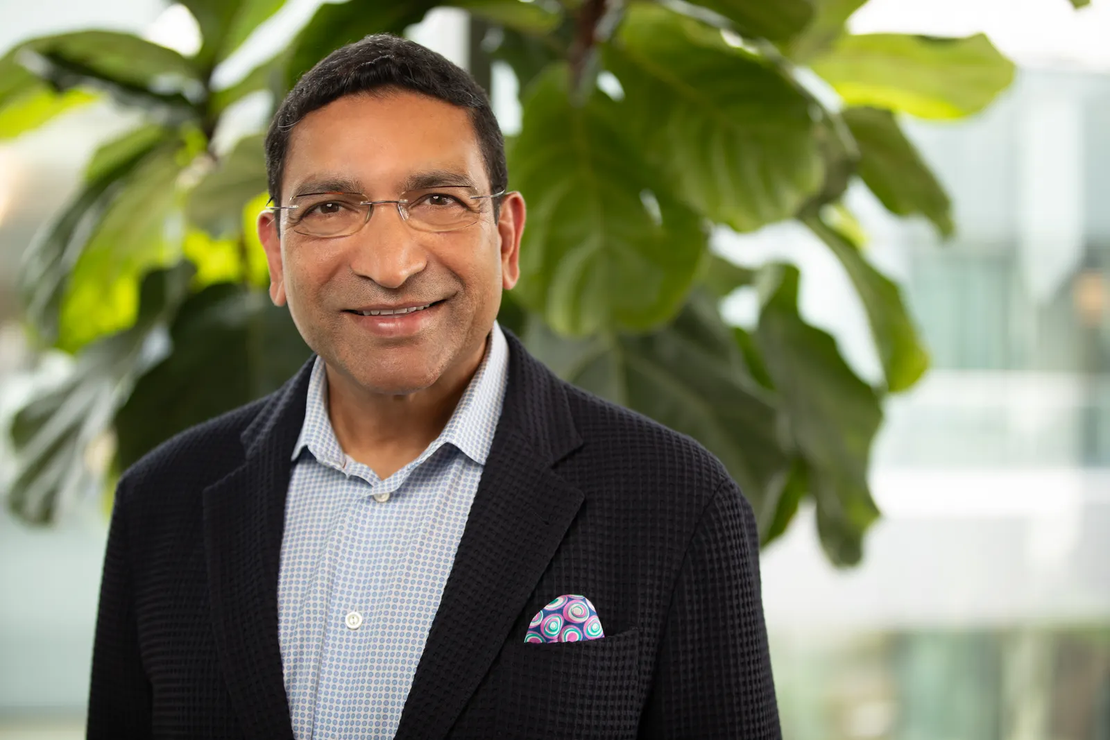 A person in a dark business suit looks straight ahead.