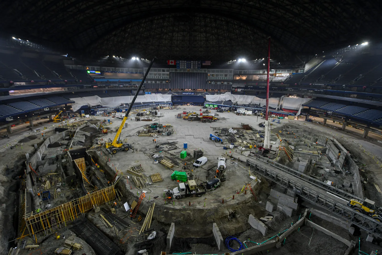 Cranes and machinery move materials in the central bowl of a professional ballpark.