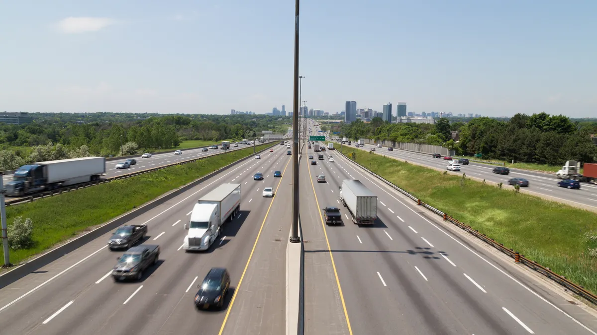 Part of Highway 401 with the Toronto skyline in the background during the day showing the blur of traffic on the road