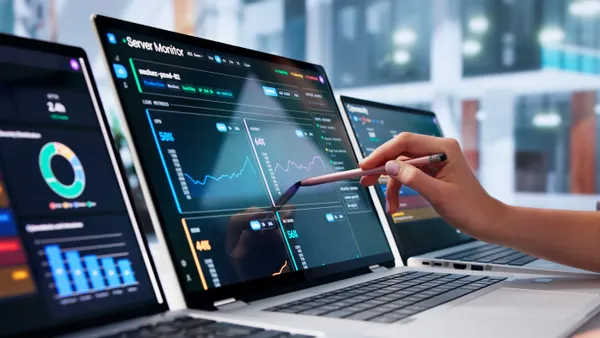Young woman monitors network data on laptop using real-time analytics.