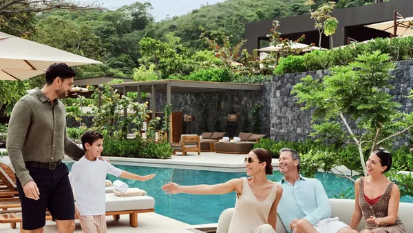 A family sits poolside at a hotel
