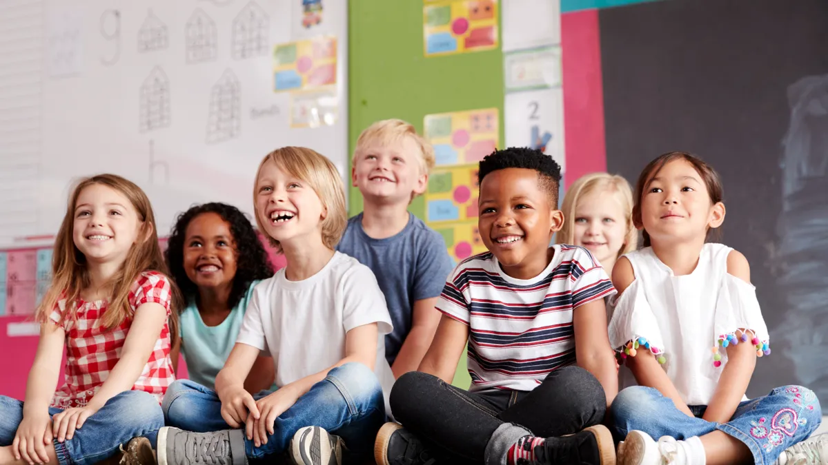 Group Of Elementary School Pupils Sitting On Floor In Classroom