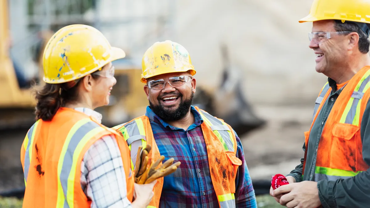 Three construction workers talking and smiling on the jobsite.