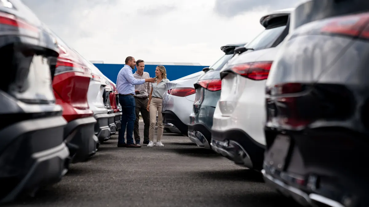 Car salesperson showing cars to a couple shopping at the dealership - stock photo