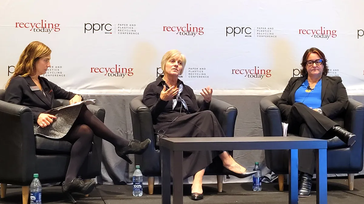 Three people sitting on a stage during a conference panel discussion.