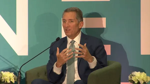 A man in a suit speak at a meeting.