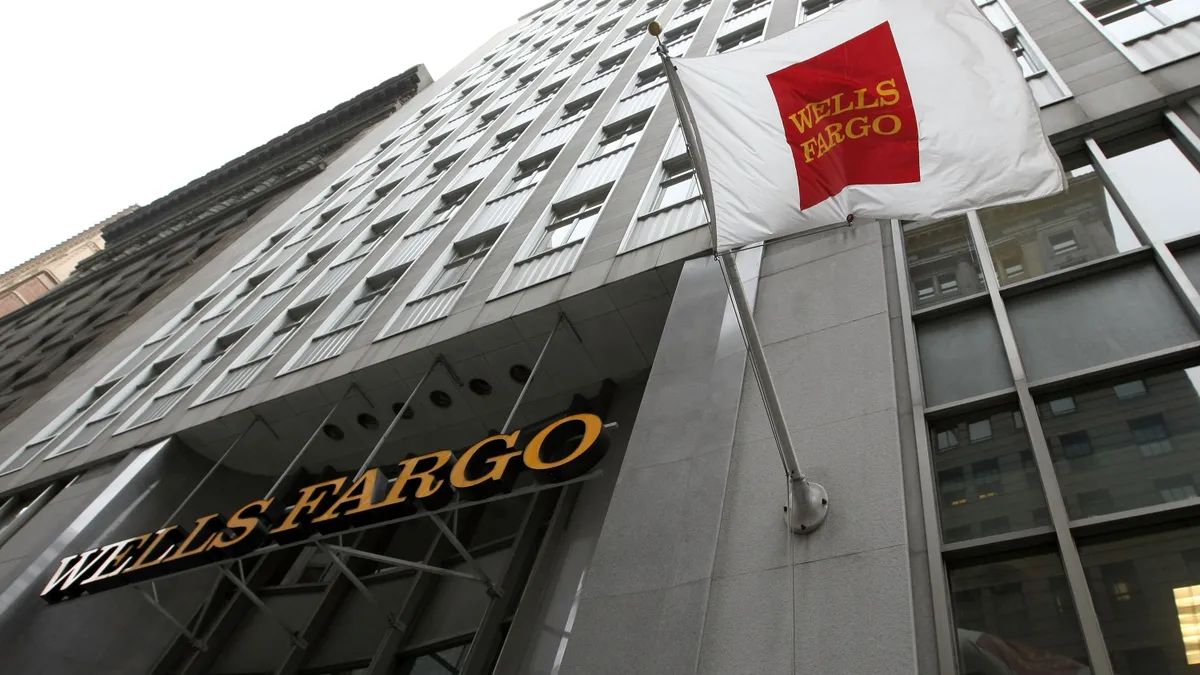 A Wells Fargo flag flies in front of a Wells Fargo bank branch.