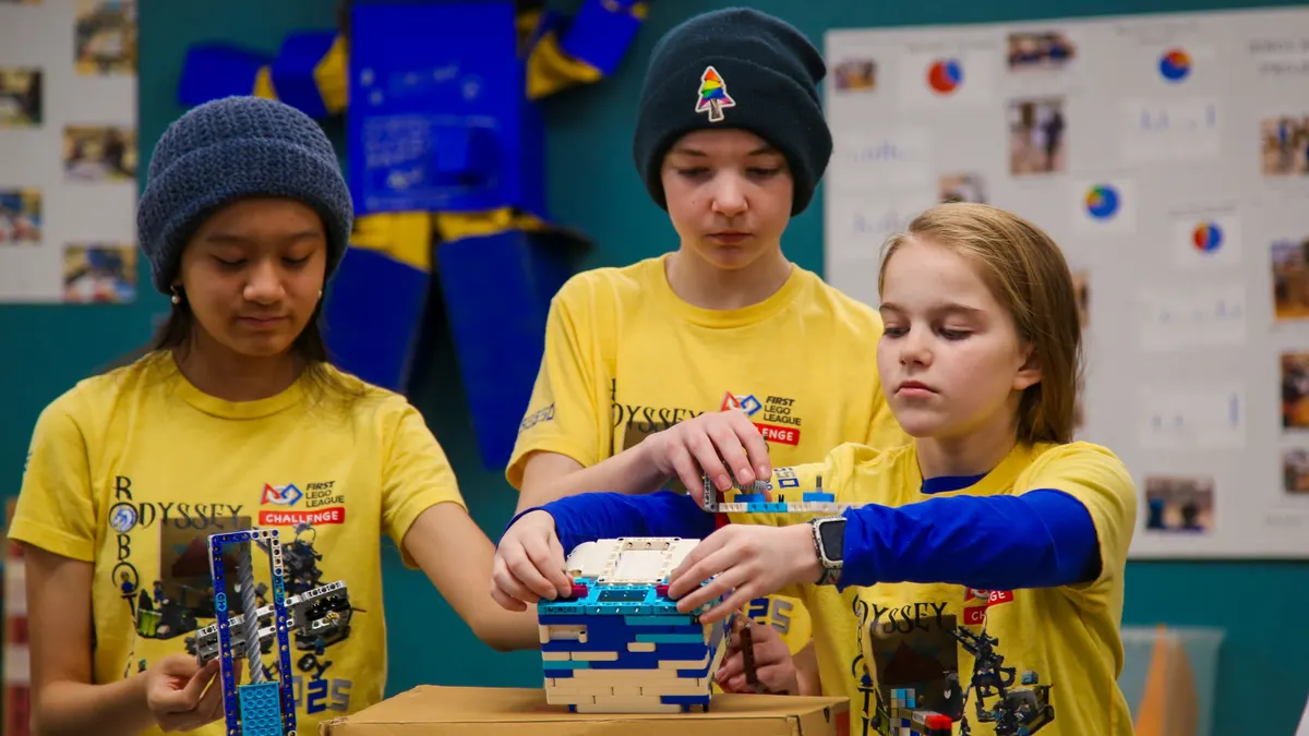 Three students work on a robotics project in a room