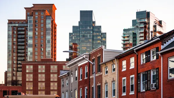 A row of brick homes with tall office buildings in the background.