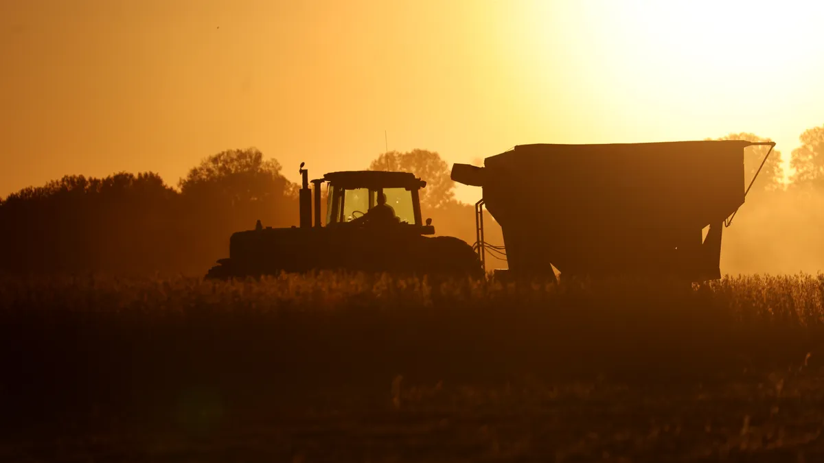 A tractor is seen in a field as the sun sets