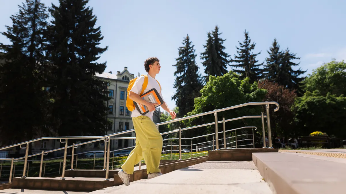 A student walks up stairs outside on campus.