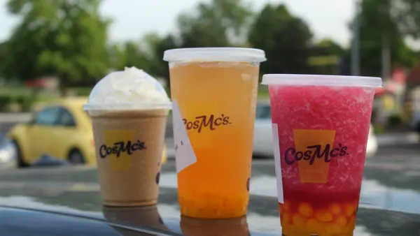Three fast food beverages stand in line.