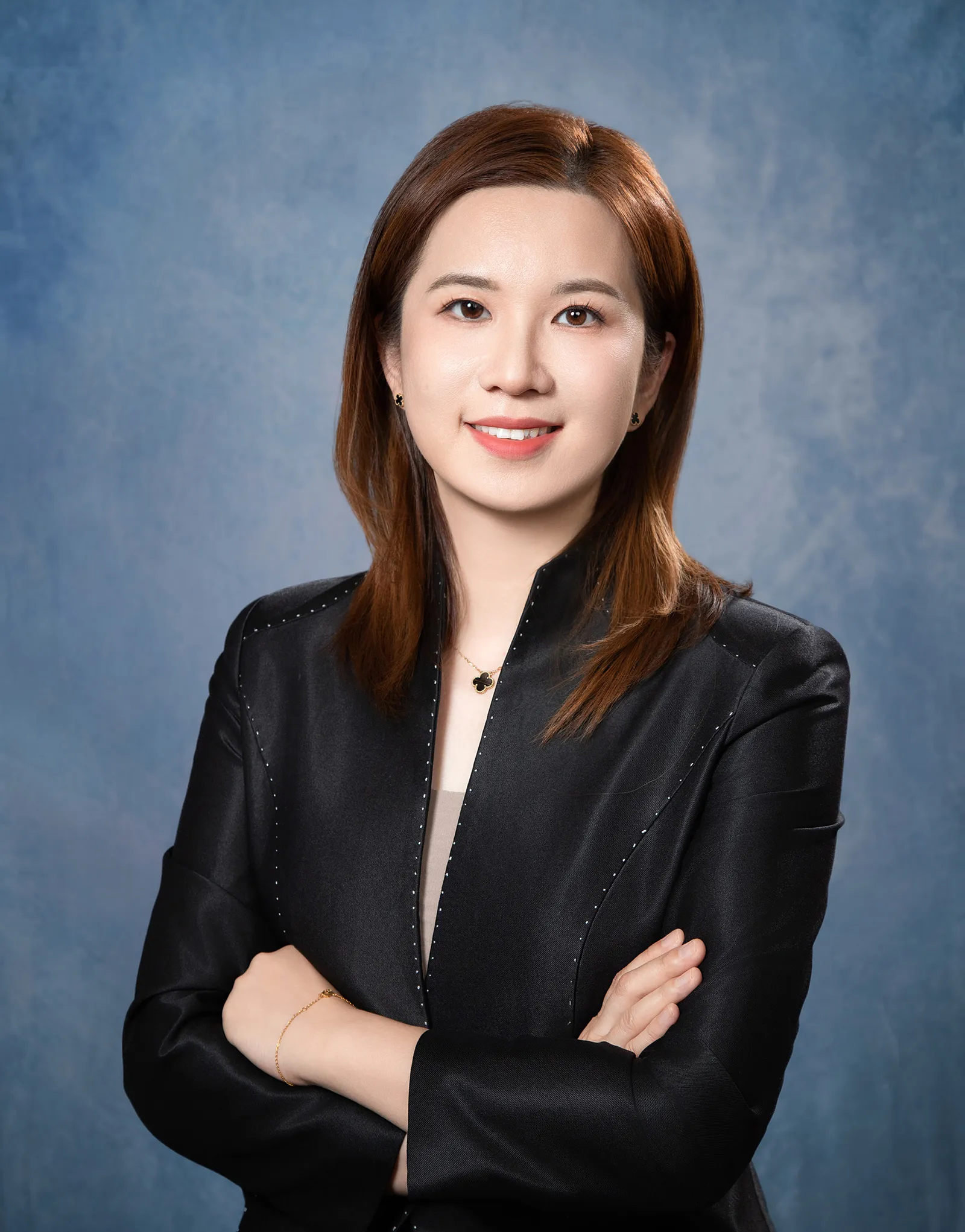 Irene Yuan stands arms crossed against grey background