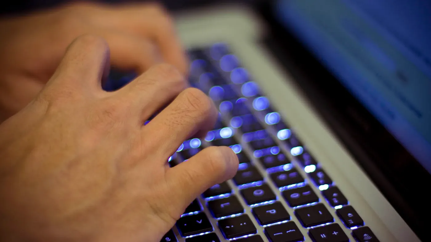 Hands type on a laptop keyboard