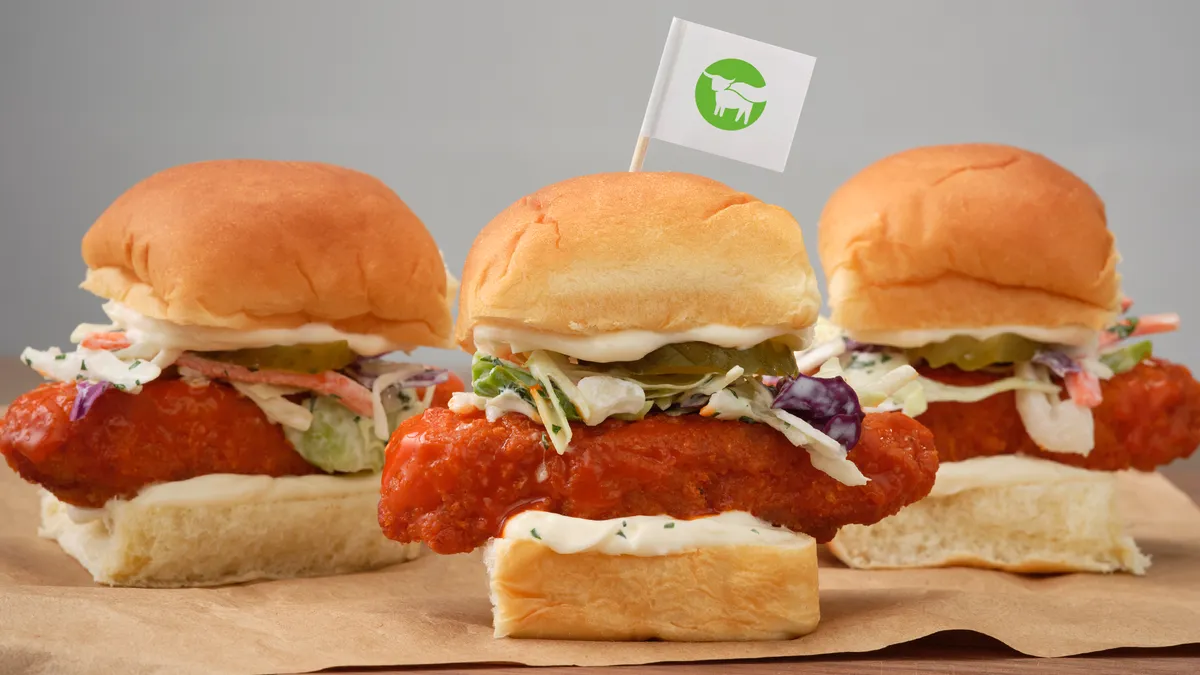 Sliders featuring Beyond Chicken in various preparations with a flag of the company logo in a bun sit on a counter.