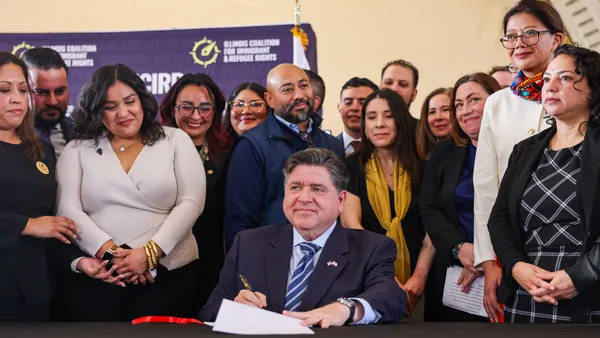 A person sits at a table surrounded by other people.