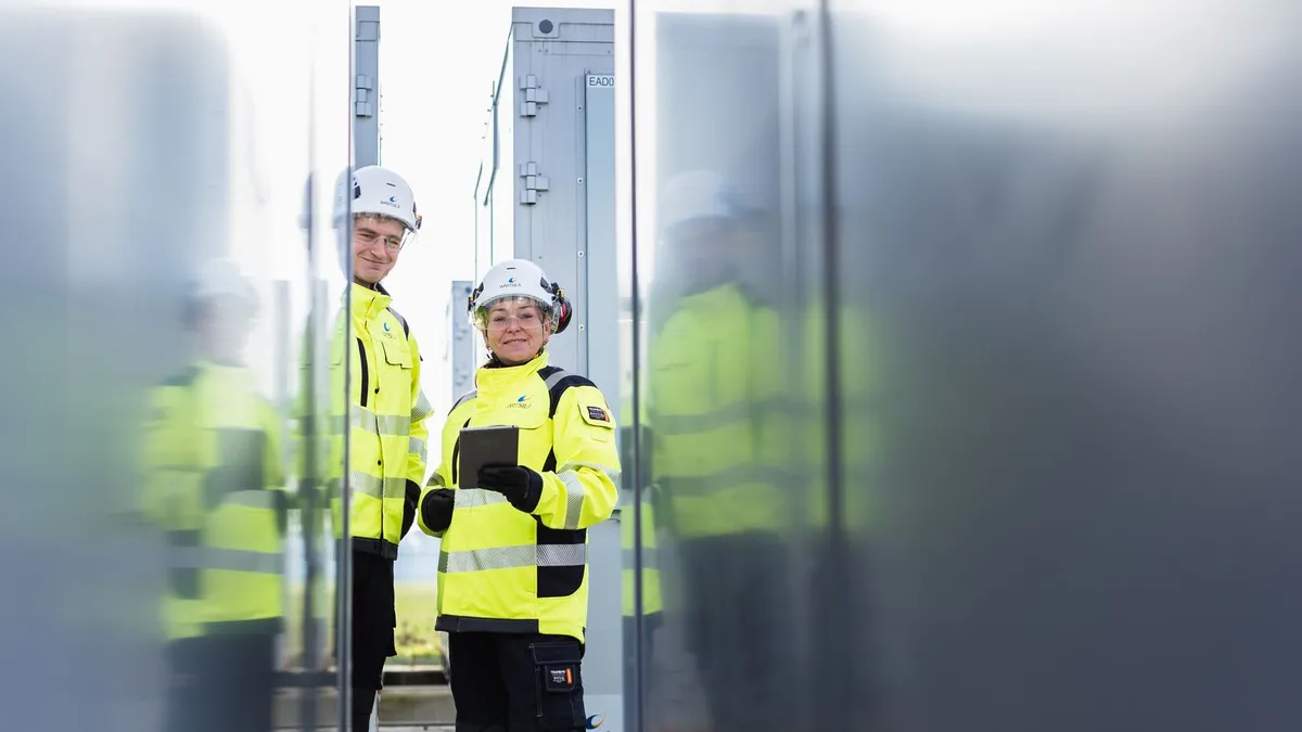 Two utility workers at a storage plant monitoring facilities.