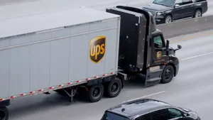 A UPS semi-truck and passenger vehicle go in opposite directions on a highway, separated by a median barrier.